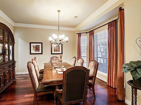 To the left of the entry is the Formal Dining room that has a wall of windows, crown molding, decorative chandelier, rich hardwood floors and is open to the butlers pantry and kitchen.