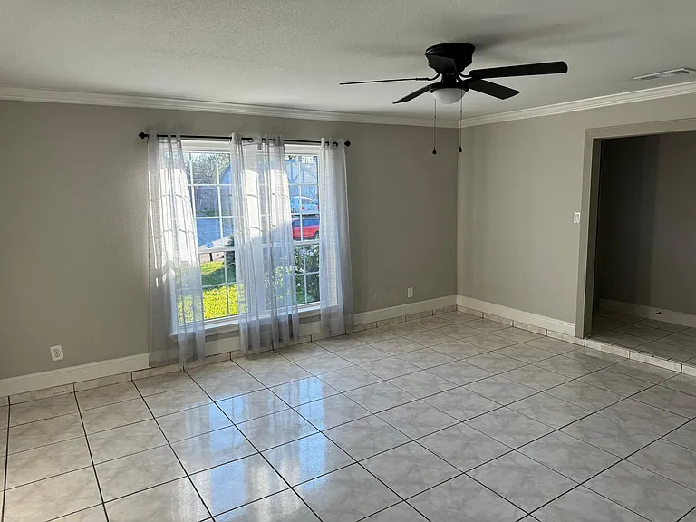 Large oversized family room, with large format white tile. New windows filling the space with nature light. New large black fan. This is the perfect space for family gatherings.