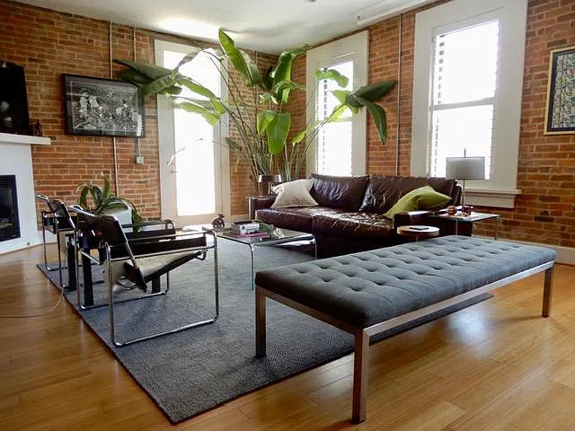 A view of the living room from the kitchen when entering the unit. Tall ceilings and southern exposure bathe the room in light. The shutters are operable and can block the light and offer privacy or be opened to allow the natural light to come in. On t