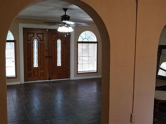 Tile floor and double doors are this living room or grand foyer is spacious and welcoming. Note the curved architecture in the windows and doorways thru out the house
