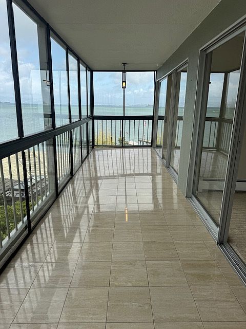Glassed in travertine deck with operable windows top and bottom with ceiling light fixture at end of deck which operates off of remote control.