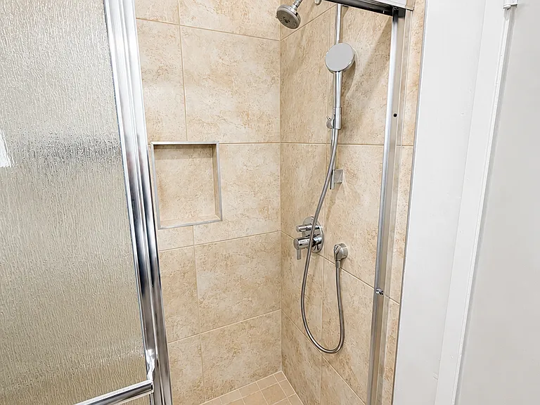 Tiled walk-in shower with glass enclosure and chrome fixtures.