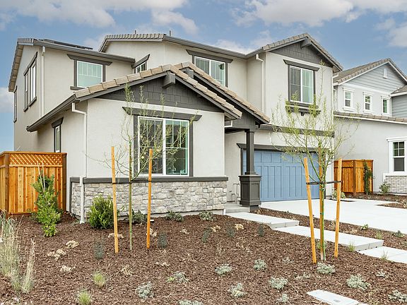 A modern two-story residential home with a landscaped front yard featuring newly planted trees and s