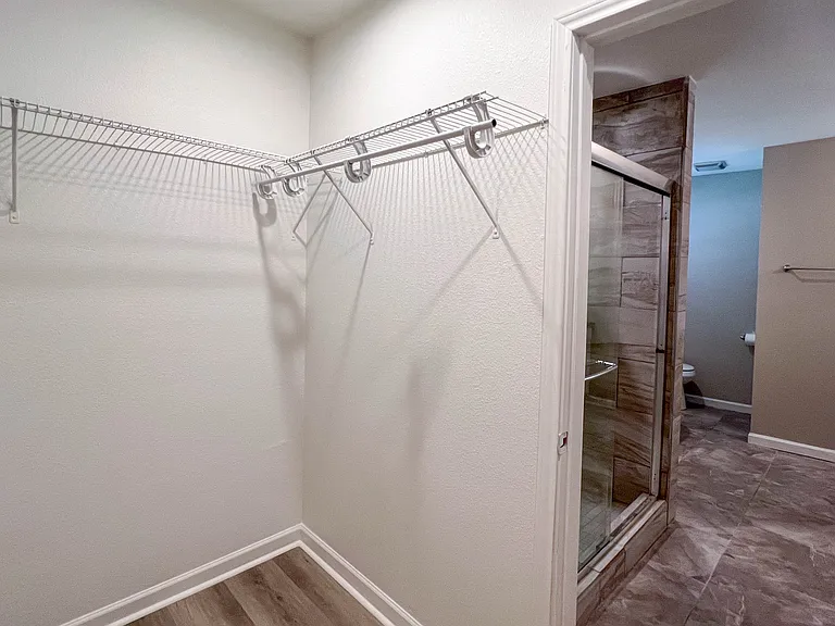 Walk-in closet with direct access to the primary bath, conveniently positioned next to the separate tiled shower.