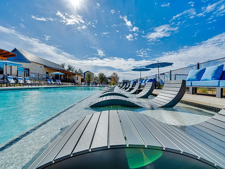 A sunny day at the outdoor pool with blue water and sun loungers.
