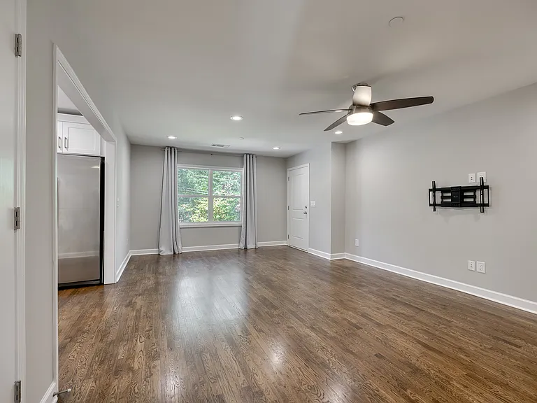 A spacious living room featuring beautifully refinished, gleaming hardwood floors and an inviting open feel.