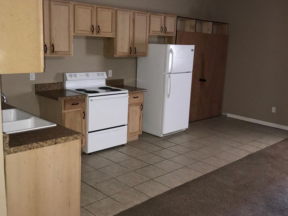 Kitchen that includes dishwasher, stove, and frig. Kitchen flows into the living room.