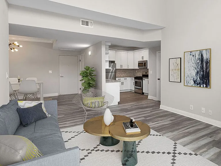 Hardwood floored living room with view of tiled kitchen and dining area.
