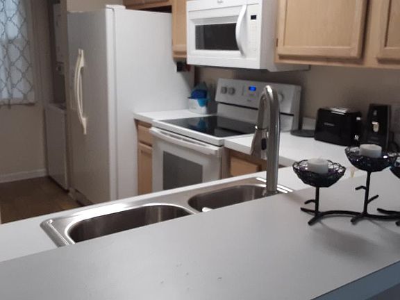 Your kitchen is conveniently laid out with white countertops and lots of cabinets. The washer-dryer combo is on the right beyond the fridge, and the pantry is opposite the washer-dryer.