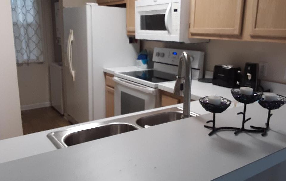 Your kitchen is conveniently laid out with white countertops and lots of cabinets. The washer-dryer combo is on the right beyond the fridge, and the pantry is opposite the washer-dryer.
