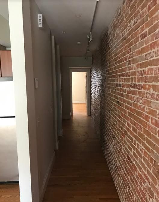 Exposed brick leading to the bathroom and the 2 bedrooms.