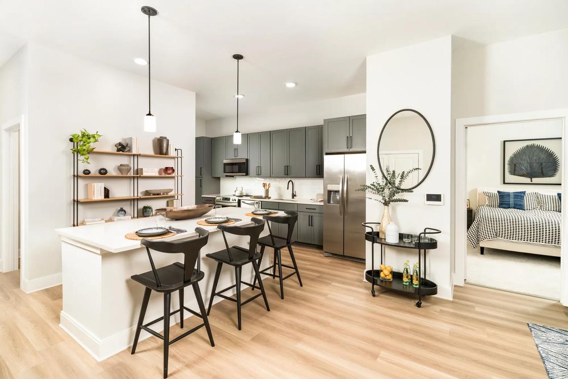 The gourmet kitchens at Modera Liberty Row offer two finish packages, including an option for modern gray cabinetry with black hardware, stainless steel appliances, white quartz countertops, and polished white horizontal tile.