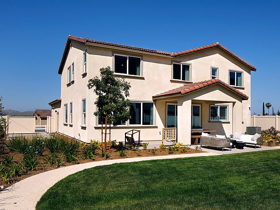 A two-story residential house with a tiled roof, surrounded by a well-maintained lawn and landscapin