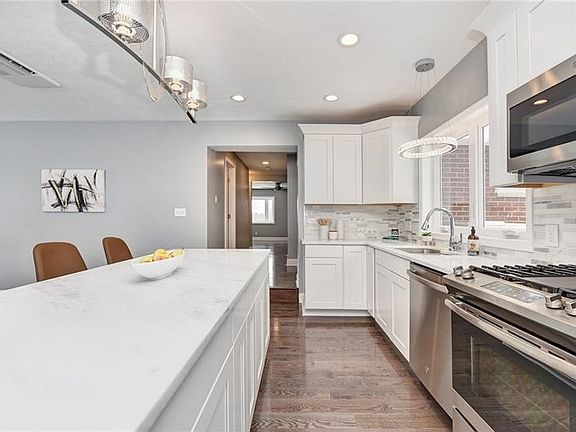 A five person island finished with a sleek white granite.