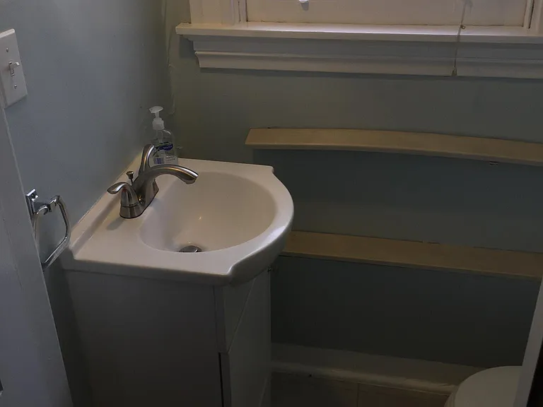 Bathroom with pedestal sink and toilet. Toilet paper furnished.