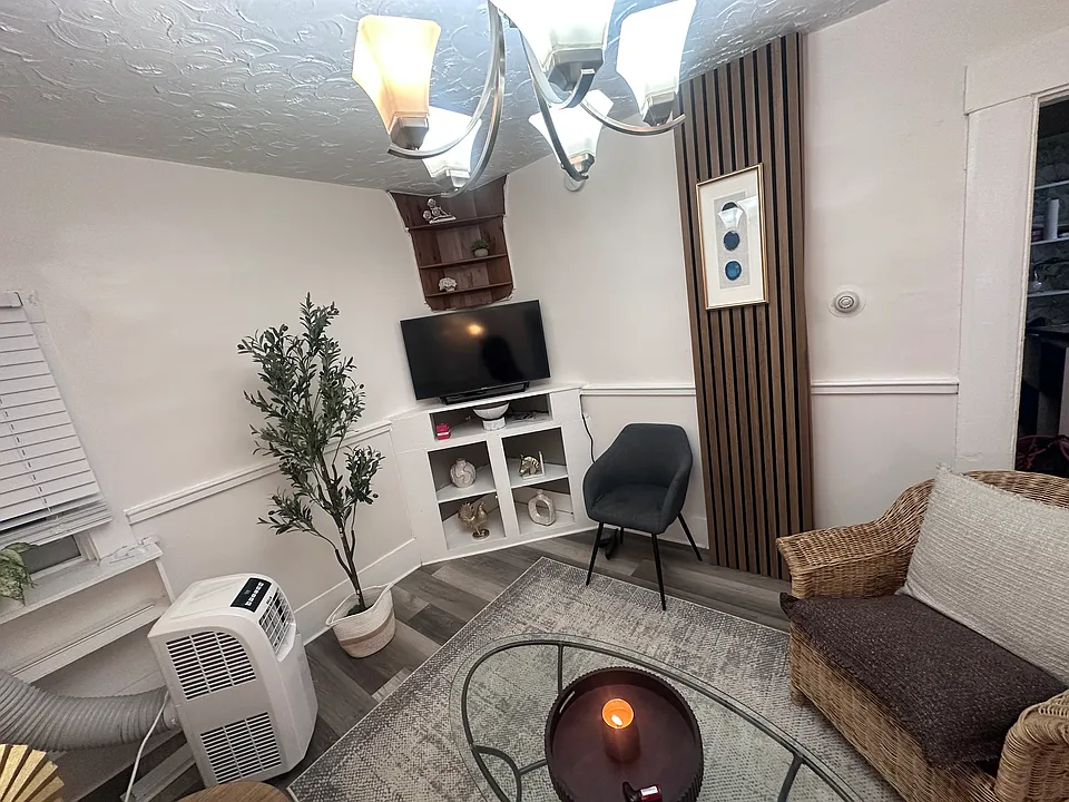 Shared living room furnished with a sofa, coffee table, side tables, television, area rug, and additional furnishings and decor