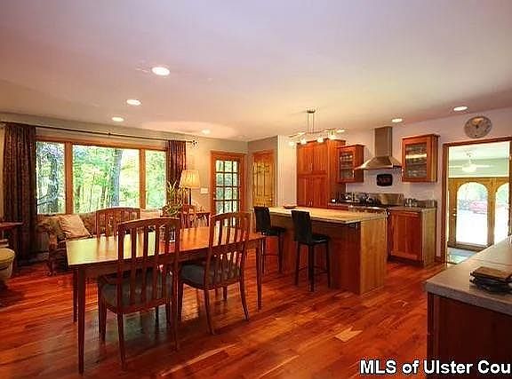 Open kitchen/dining room with cherry floors and high-end cabinets, stainless steel appliances and cement countertops