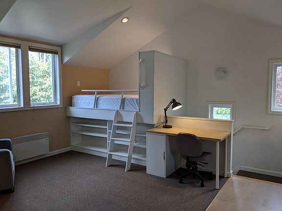 Loft-style double bed (small ladder access), built-in bookcase, desk with extra storage. Notice all the windows and the tall ceiling! Private stairwell enters at the back right.