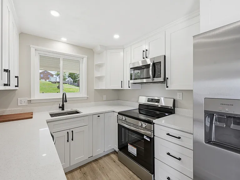 Renovated kitchen with stainless steel appliances, garbage disposal, quartz counters, undermount sink with custom inserts, soft-close drawers/door, and LED lighting.