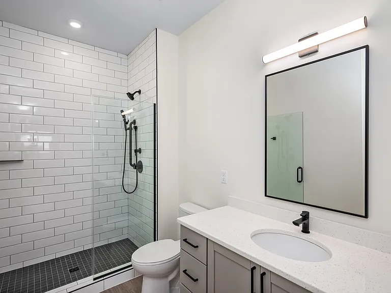 Contemporary bathroom featuring a sleek glass shower, modern vanity with a quartz countertop, and elegant lighting. Contemporary bathroom featuring a sleek glass shower, modern vanity with a quartz countertop, and elegant lighting.