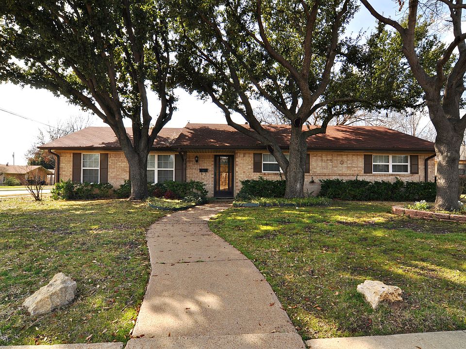 Single story home surrounded by beautiful shade trees.