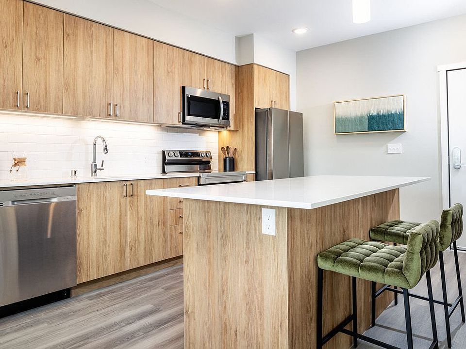 Kitchen with oak cabinetry, white granite countertops, white tile backsplash and stainless steel appliances