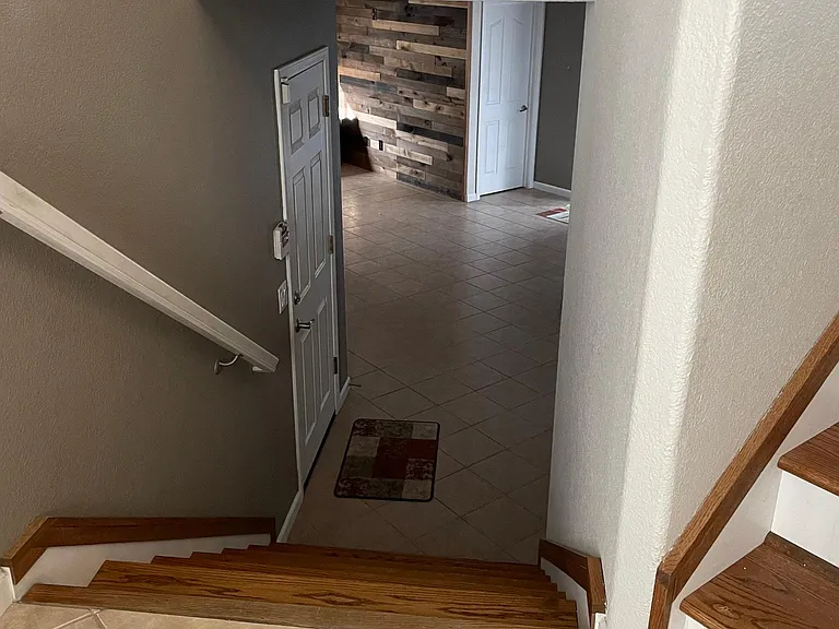 Looking down to den area from front door entrance. Stairs to upper level on right