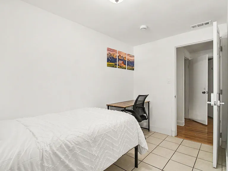 Private bedroom with a comfortable bed, dedicated desk/workspace, and easy access to the hallway for added convenience.