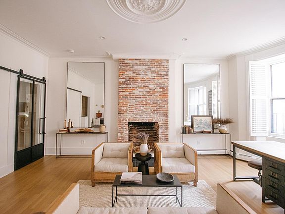 Sunny & bright living room with decorative fireplace, oversized windows with plantation shutters for privacy.