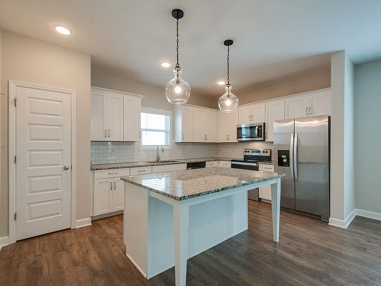 The kitchen boasts lots of cabinet space, granite countertops, stainless steel appliances and a tiled backsplash.