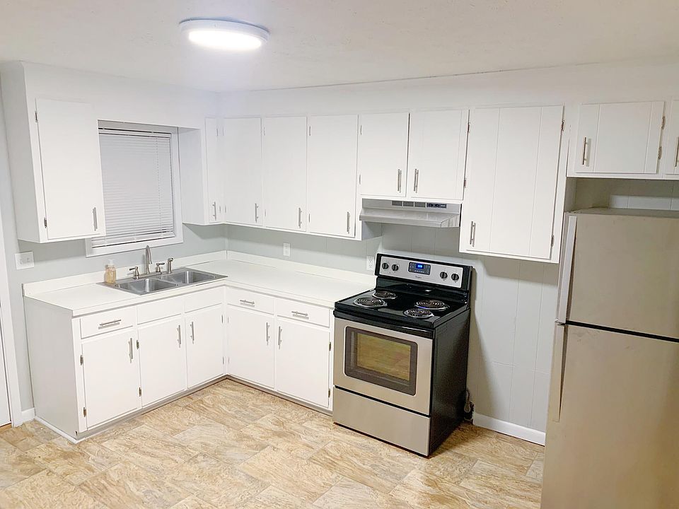 Kitchen with refinished cabinets and new stainless steel appliances. Window looks onto back porch and large backyard surrounded by woods.