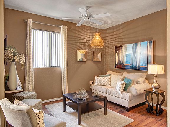 A living room with a ceiling fan and window overlooking the property