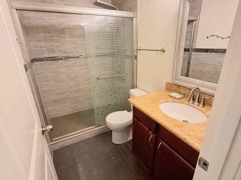 Brightly lit, dimmable vanity with walk-in waterfall shower.