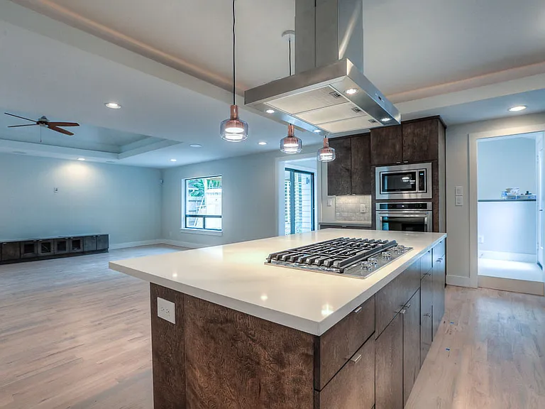 Kitchen island with gas cooktop and stainless hood, open to the great room and adjacent utility room