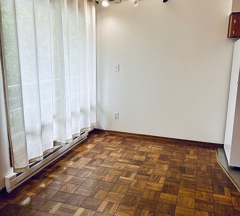 Dining area just off the kitchen with floor to ceiling window and parquet wood flooring throughout.