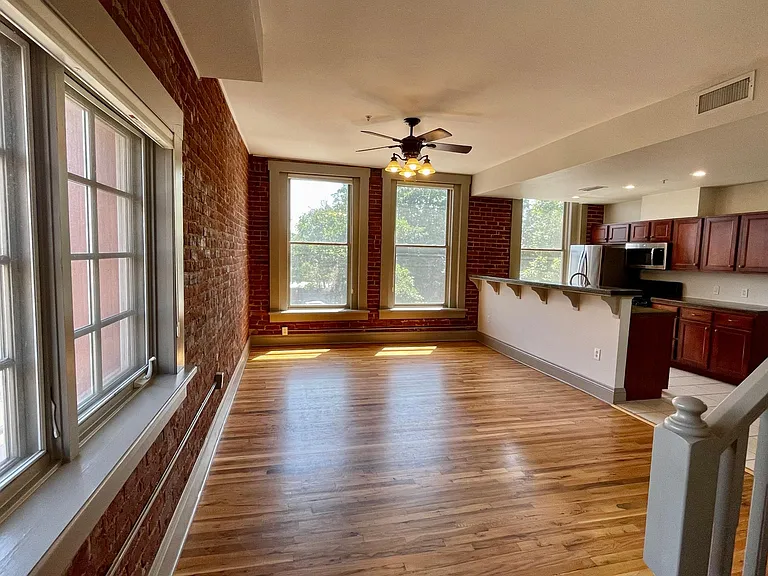 Main living space with exposed brick and hardwood floors