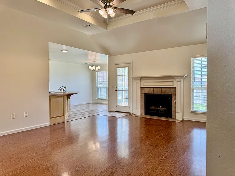 Spacious living room with hardwood floors, gas fireplace with tile surround, and French door to the backyard