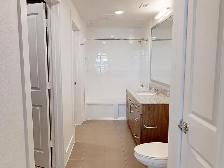 Apartment bathroom with large soaking tub and tile flooring.