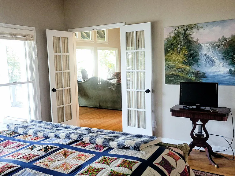 From primary bedroom looking through french doors to great room and picture windows lake front.