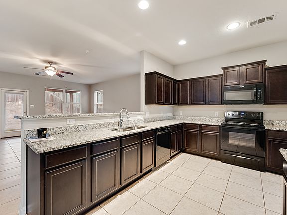 Kitchen featuring black appliances, dark brown cabinets, tile patterned flooring, and lovely granite countertops.