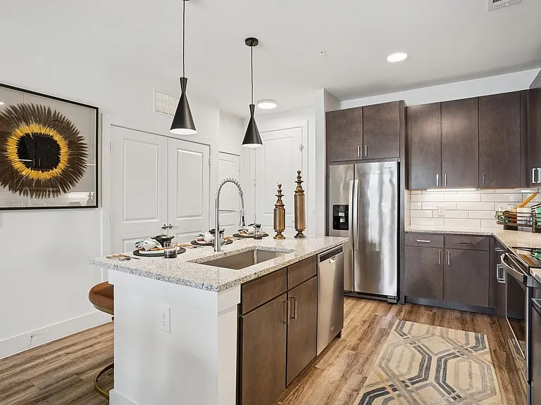 Kitchen with espresso cabinetry, speckled granite countertops, white tile backsplash, stainless steel appliances, and hard surface flooring