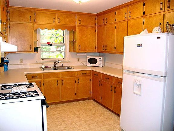 Kitchen is equipped with white appliances and naturally stained cabinets.