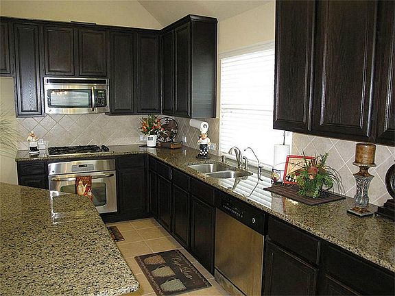 Framed by large windows, the charming breakfast area offers an inviting and light and bright setting featuring window seats, tile flooring, 2" blinds and a pretty light fixture!