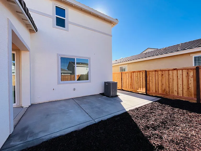 Backyard with extended concrete and low maintenance mulch