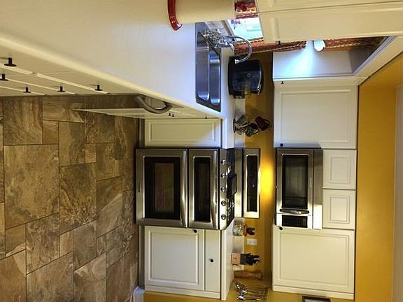 Kitchen features clean white cabinetry and stainless appliances.