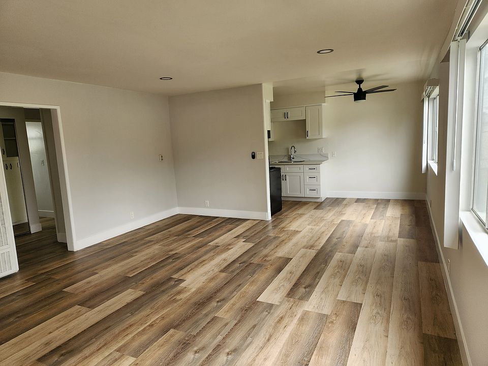 Large living room with wood look plank flooring and large windows.