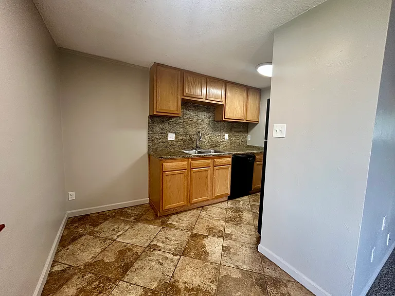 Charming kitchen with elegant wood cabinetry, granite backsplash, and tiled floor, offering a warm and inviting atmosphere. Charming kitchen with elegant wood cabinetry, granite backsplash, and tiled floor, offering a warm and inviting atmosphere.