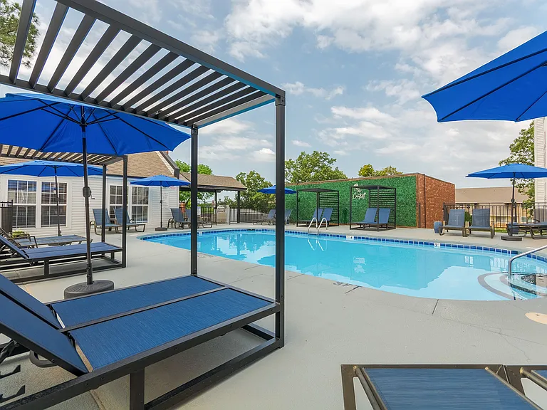 A sparkling swimmin gpool with sundeck and tandem chaise lounge chairs is shown at ReNew on Cantrell.