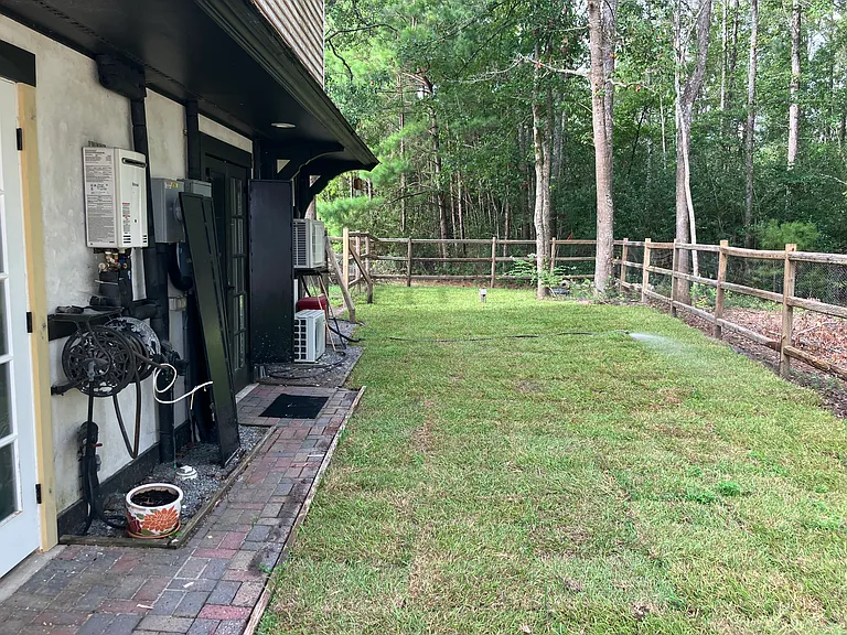 Nice green yard surrounded by pines and with view to pond with fish