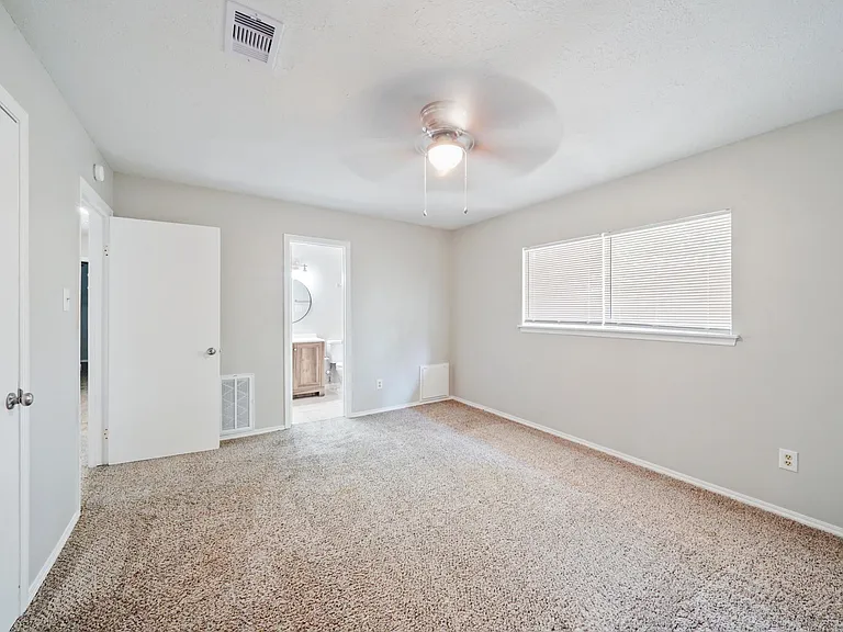 primary bedroom with 2 closets & its own bathroom